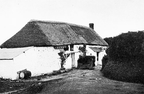 One of plaster and thatch, overgrown with roses.